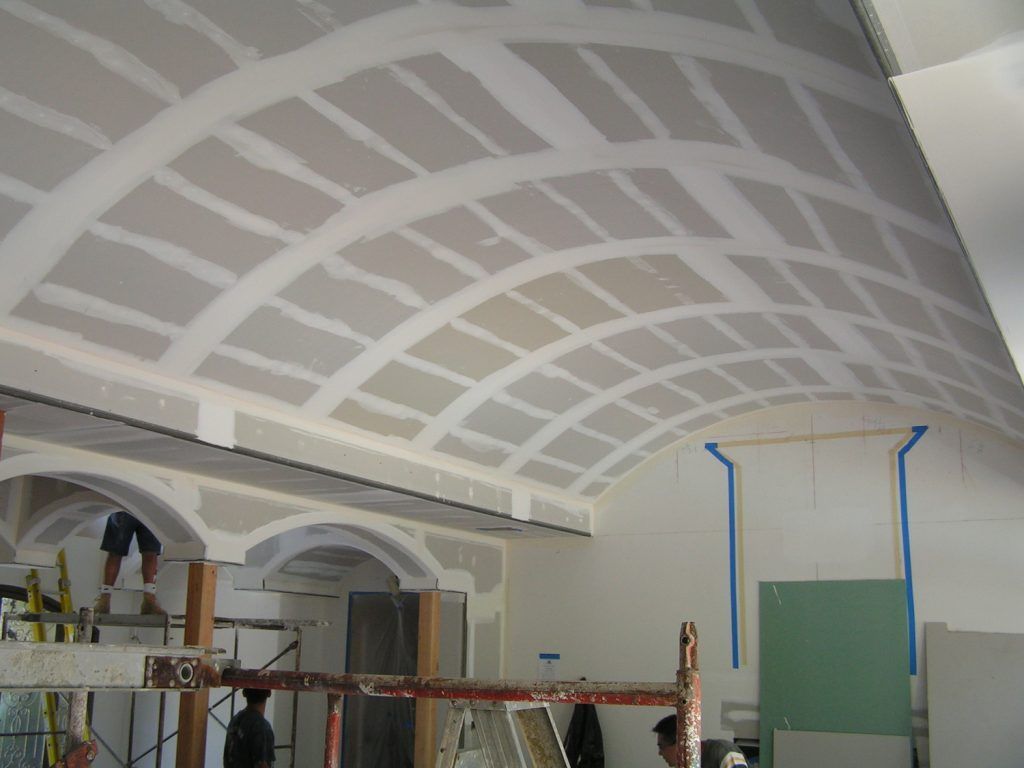 A man is standing on a ladder in front of a ceiling that is being built