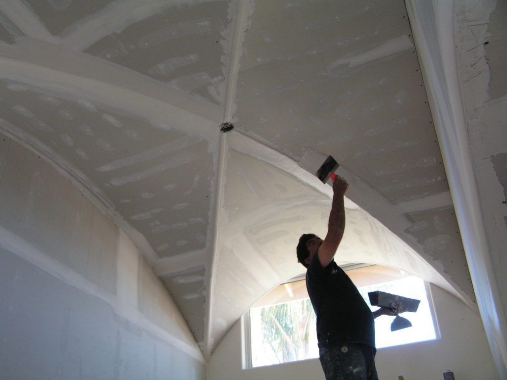 A man is working on a ceiling with a spatula.