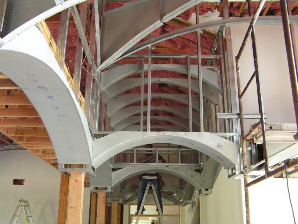 A man is standing on a ladder in a building under construction