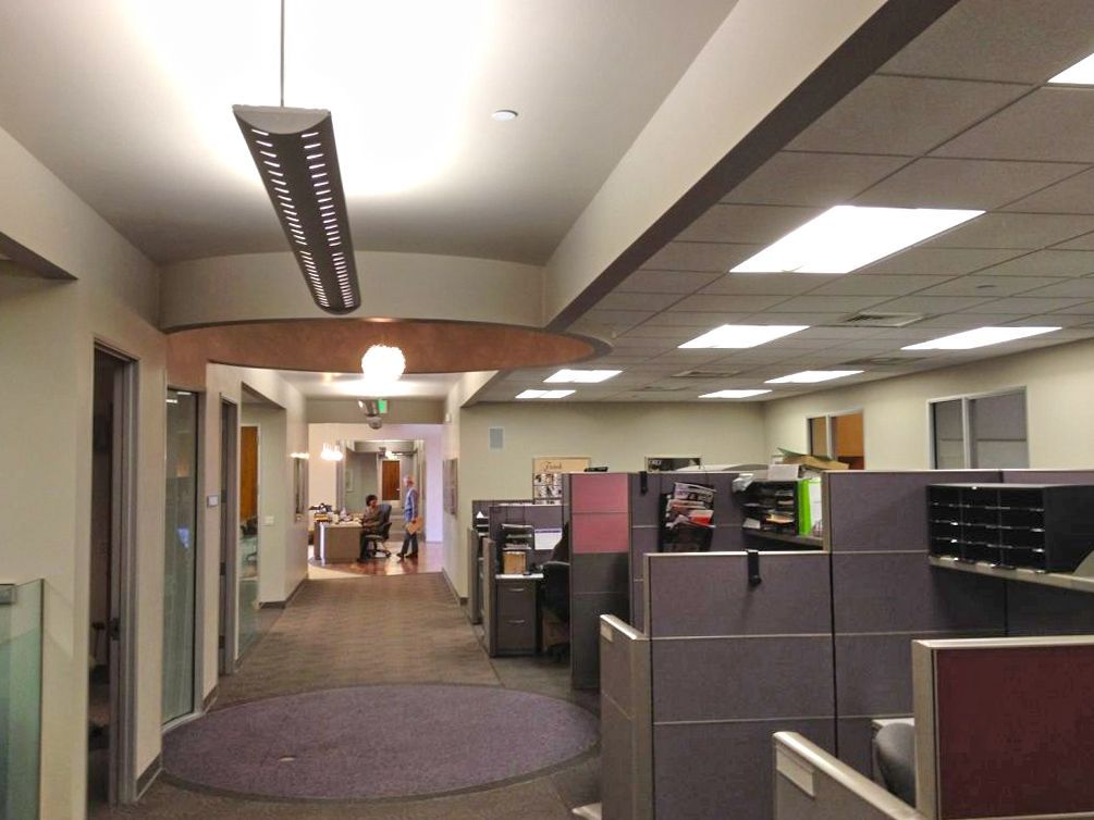 A hallway in an office with cubicles and a purple rug