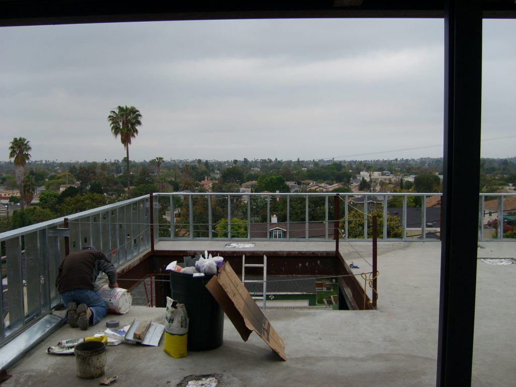 A man is working on a rooftop deck with a view of a city