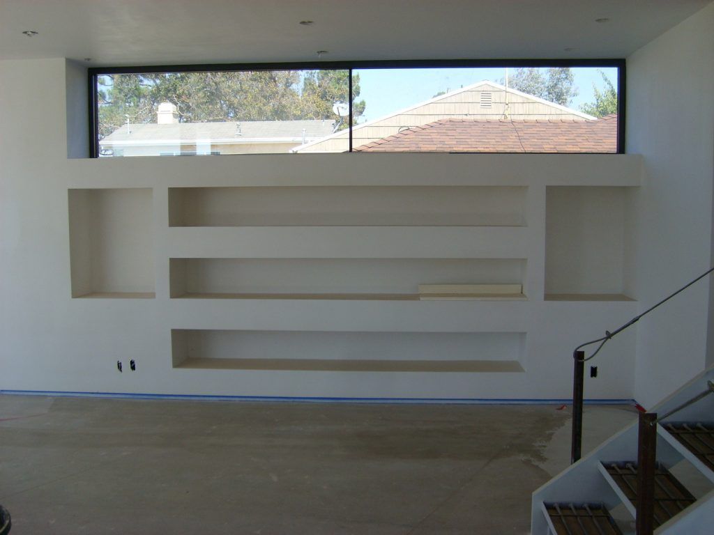 An empty room with shelves and stairs and a large window