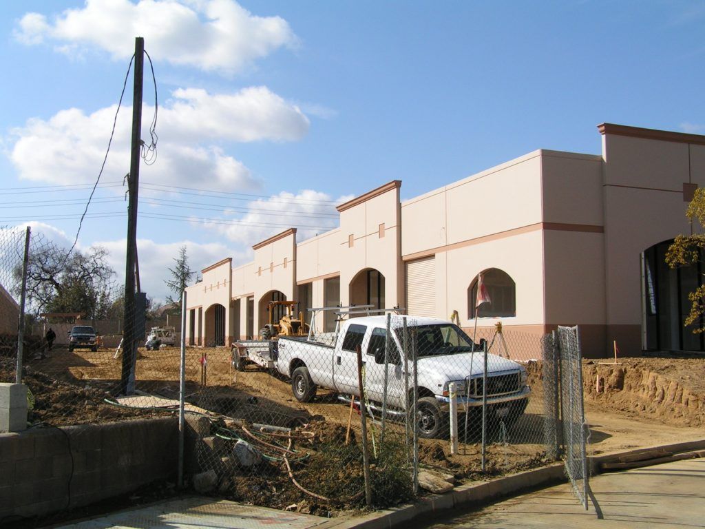 A white truck is parked in front of a building under construction