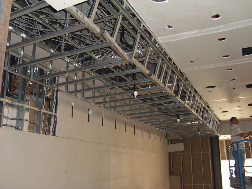 A man is working on the ceiling of a building under construction.