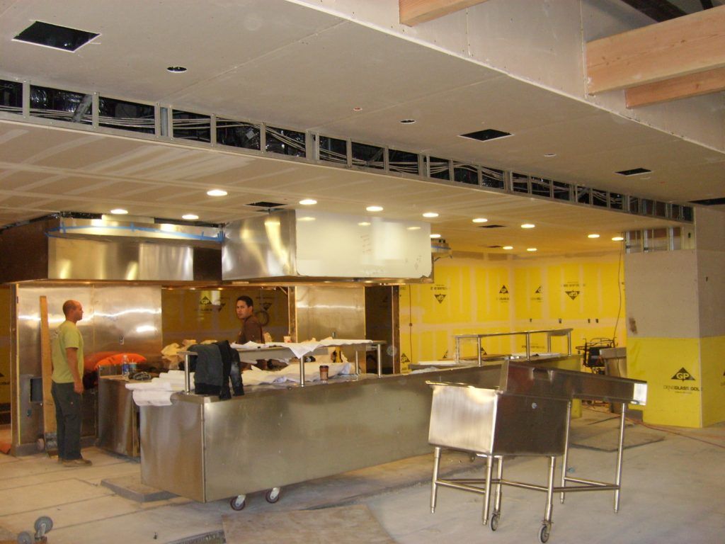A man stands at a counter in a kitchen under construction
