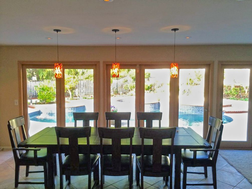 A dining room with a table and chairs and a pool in the background