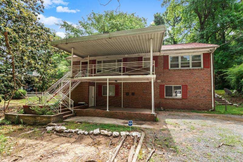 A red brick house with a covered porch and stairs is for sale.