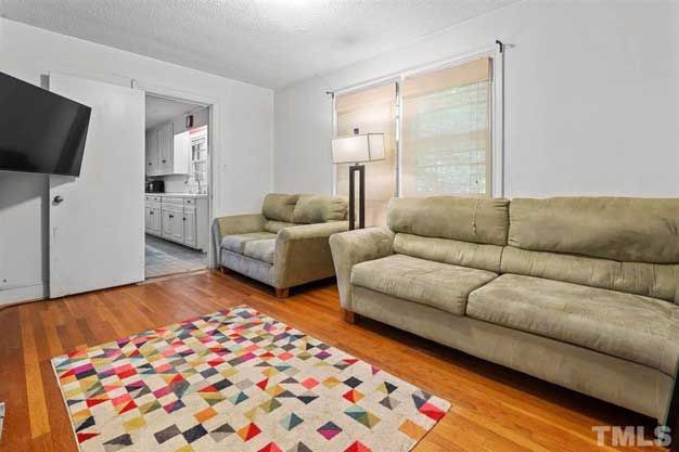 A living room with two couches , a rug , and a flat screen tv.