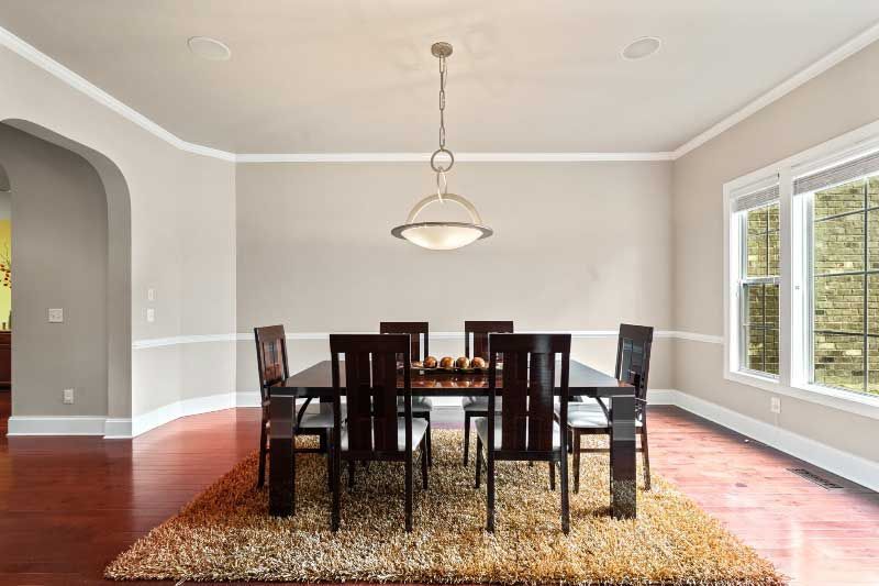 A dining room with a table and chairs and a rug.