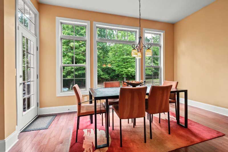 A dining room with a table and chairs and a rug.