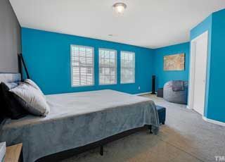 A bedroom with blue walls and a bed.