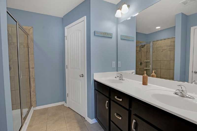 A bathroom with two sinks , a large mirror and a walk in shower.