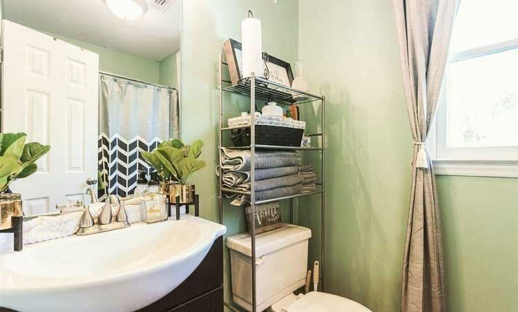 A bathroom with a sink , toilet , mirror and towel rack.