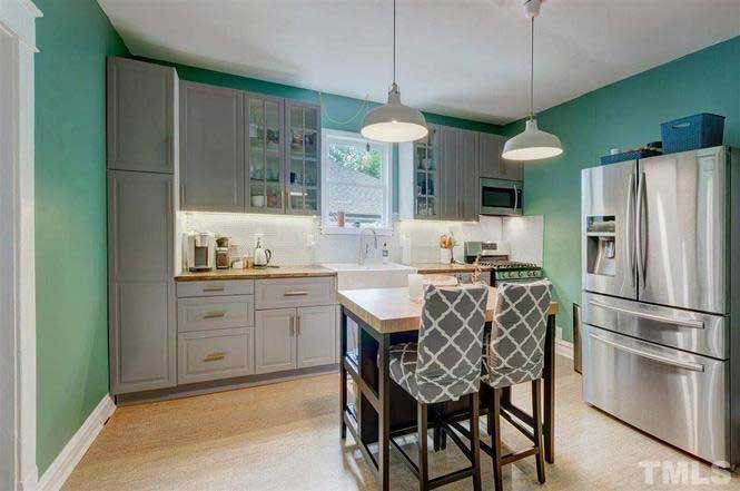 A kitchen with stainless steel appliances , gray cabinets and green walls.