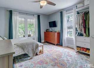A bedroom with a bed , dresser , television and ceiling fan.