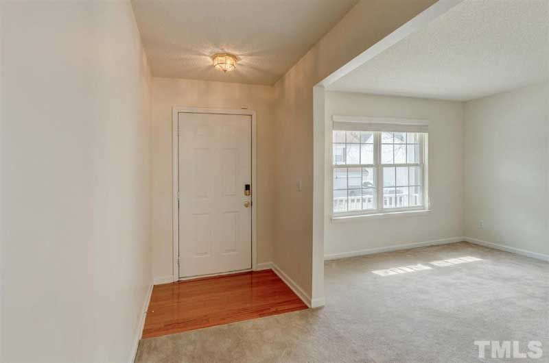 A hallway in a house with a door and a window.