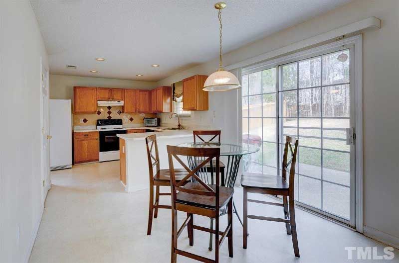 A kitchen with a table and chairs and a sliding glass door.