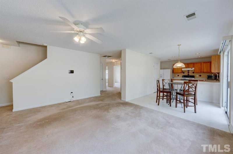 A living room with a table and chairs and a ceiling fan.