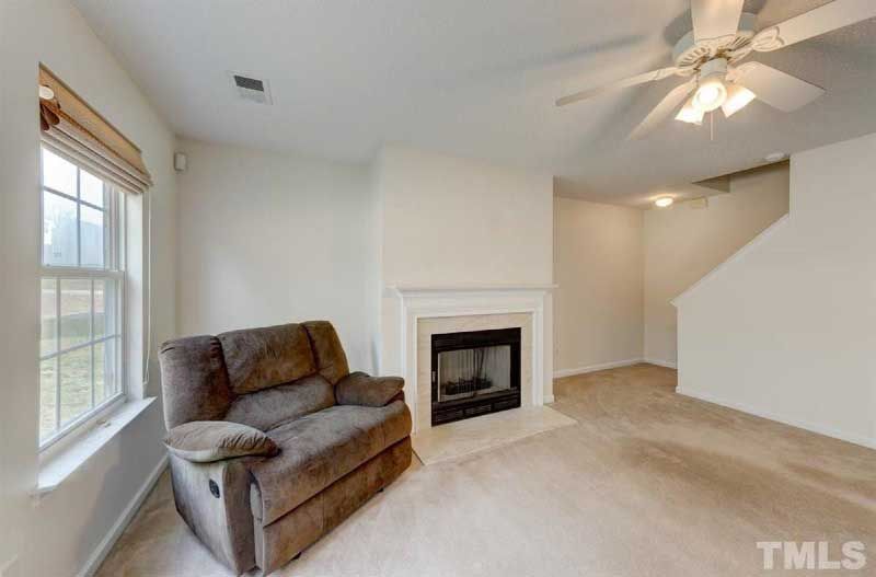 A living room with a couch , chair , fireplace and ceiling fan.