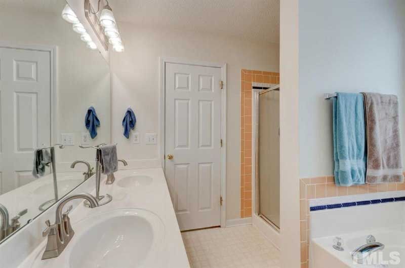 A bathroom with two sinks , a tub and a shower.