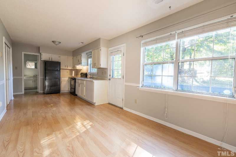 An empty living room with hardwood floors and a kitchen.