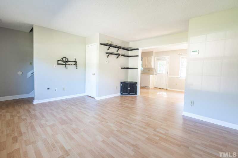 An empty living room with hardwood floors and white walls.