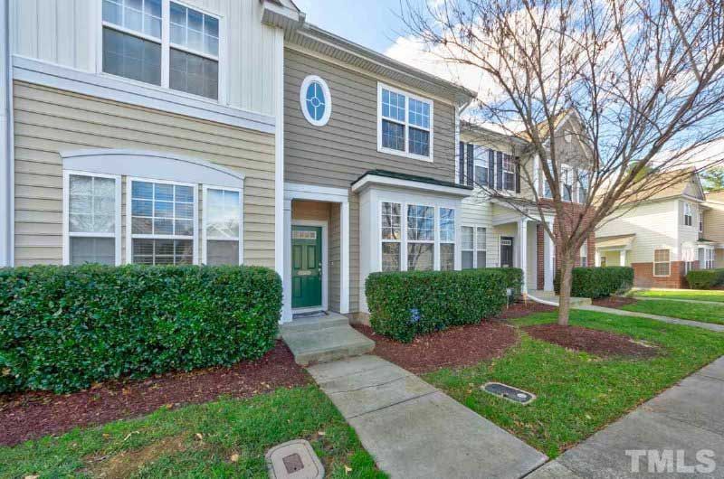 A house with a lot of windows and a green door is for sale.