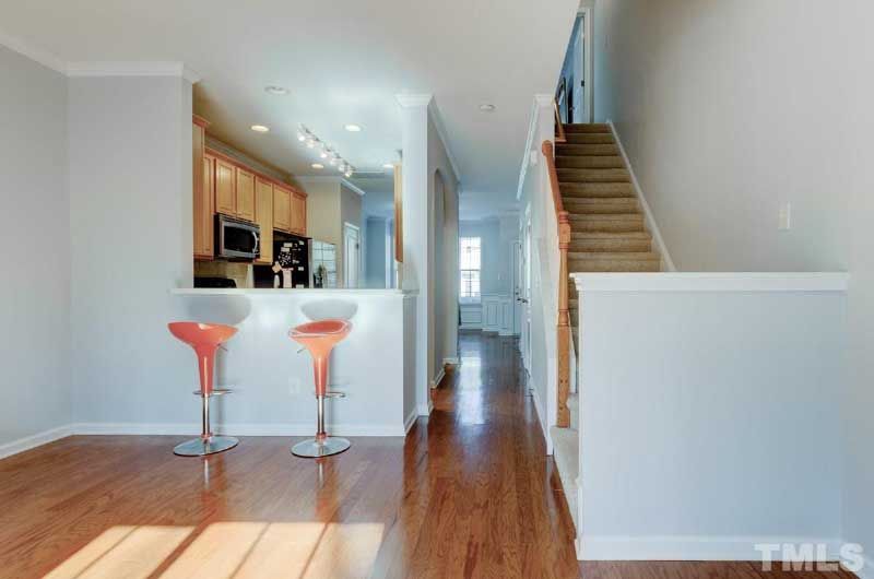 A living room with hardwood floors and two orange bar stools