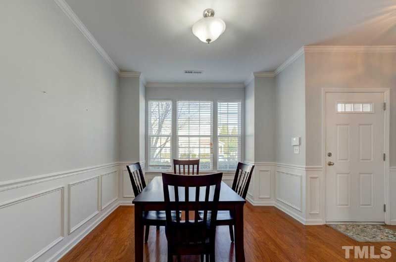 A dining room with a table and chairs and a door that says tmls