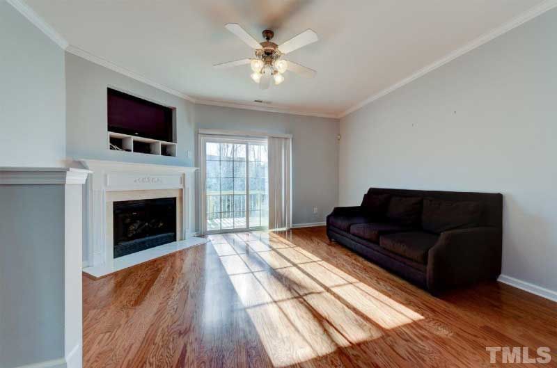 A living room with a couch , fireplace and ceiling fan.