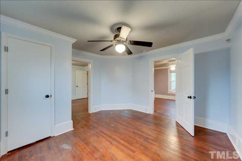 An empty room with hardwood floors and a ceiling fan.
