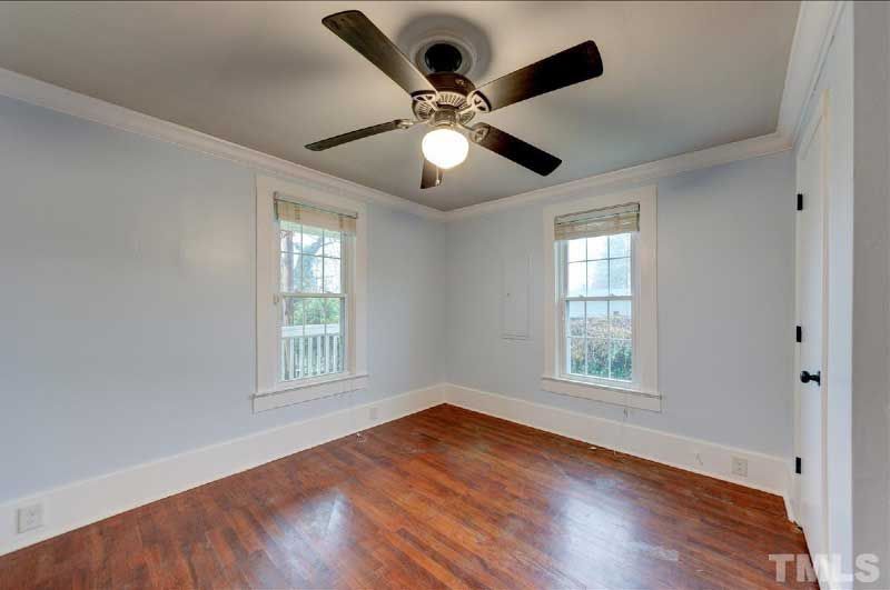 An empty bedroom with hardwood floors and a ceiling fan.