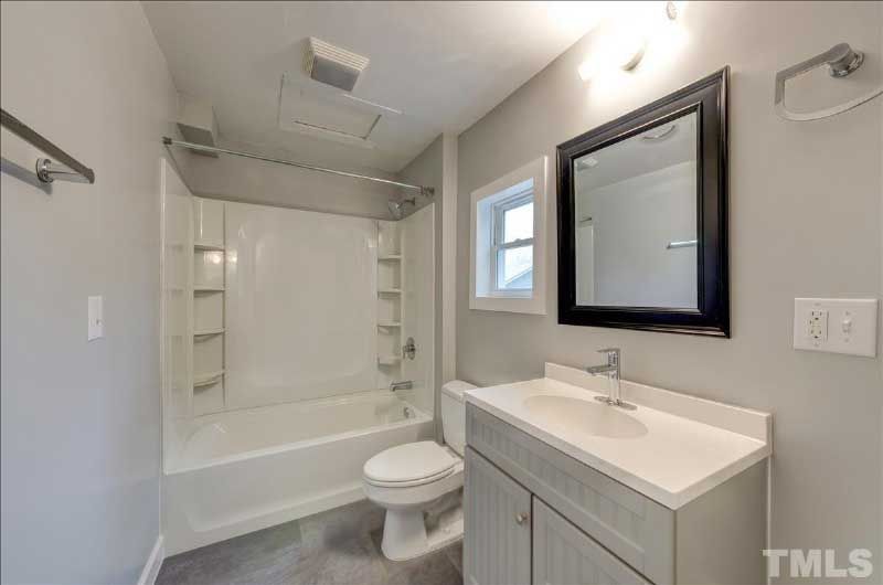 A bathroom with a toilet , sink , tub and mirror.