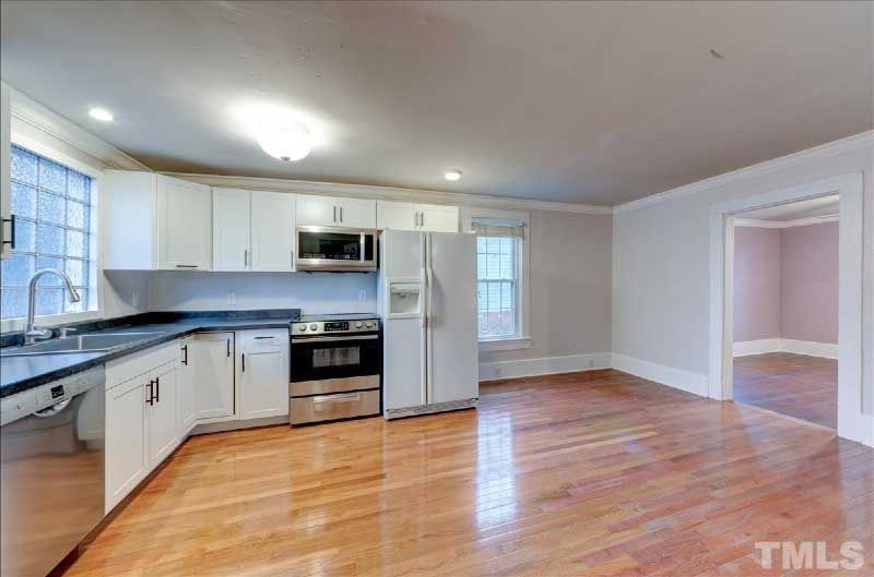 A kitchen with white cabinets , stainless steel appliances , and hardwood floors.