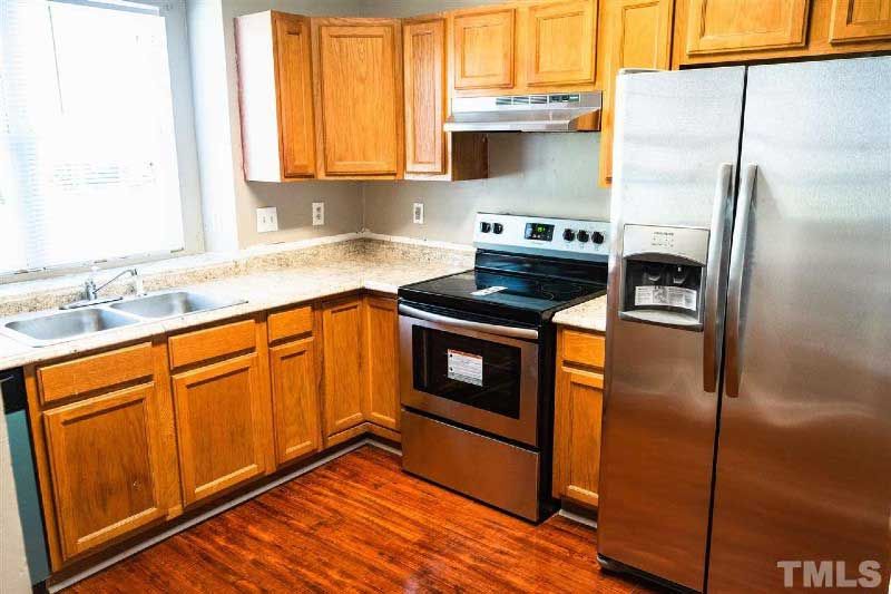 A kitchen with stainless steel appliances and wooden cabinets.
