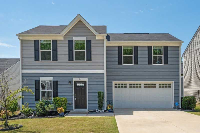 A large gray house with black shutters and a white garage door.