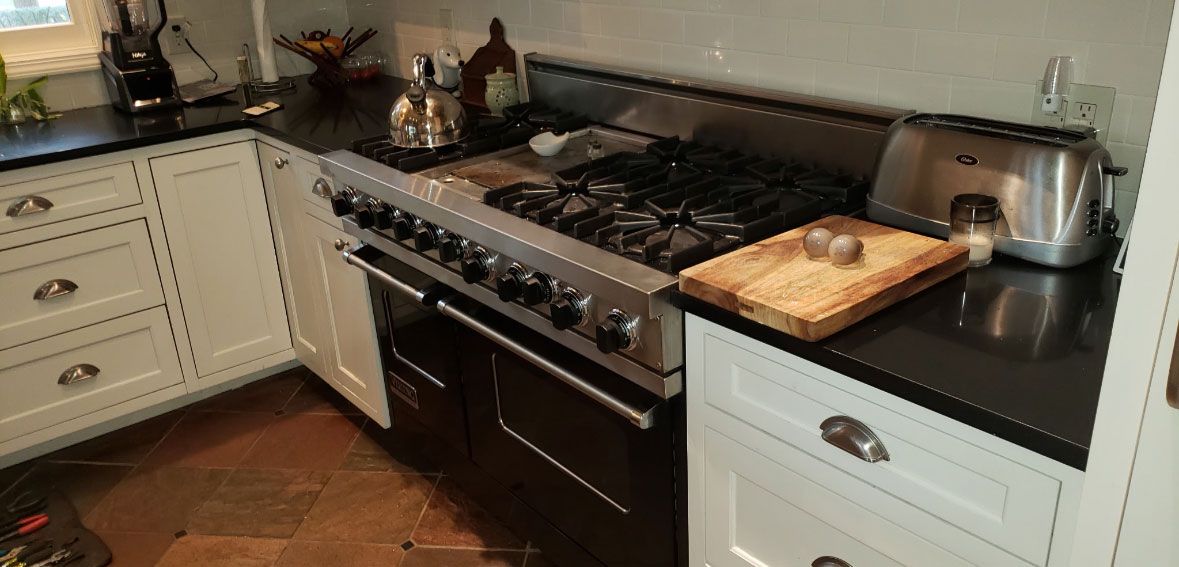 A kitchen with a stove , oven , toaster and cutting board.