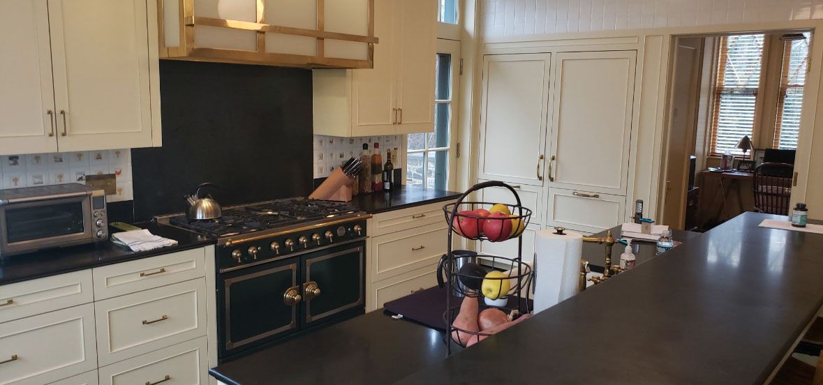 A kitchen with white cabinets , black counter tops , a stove and a large island.