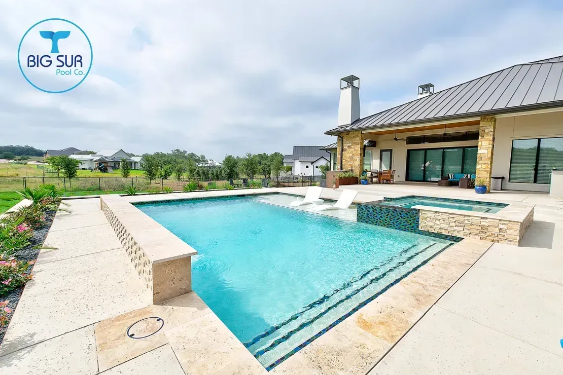 Modern stone house with a turquoise backyard pool and countryside views