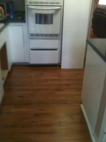 A kitchen with a wooden floor and white cabinets
