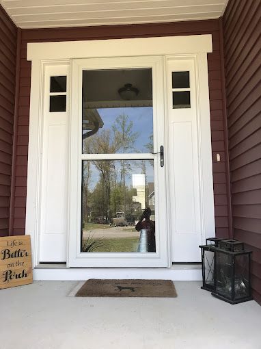 The front door of a house with a sign on the porch.