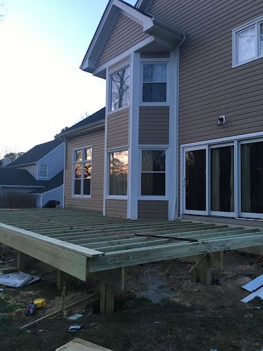 A wooden deck is being built in front of a house.