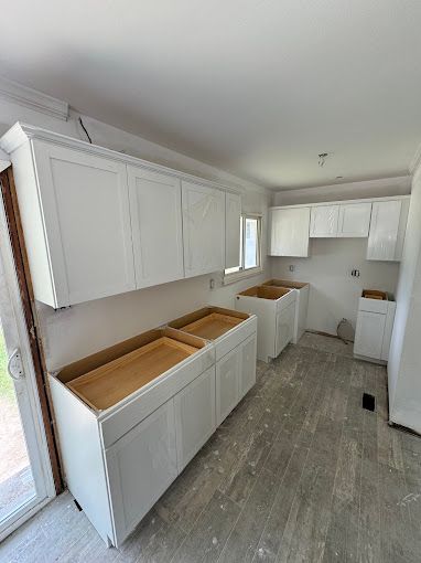 A kitchen with white cabinets and wooden counter tops is being remodeled.