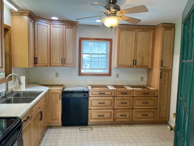 A kitchen with wooden cabinets and a black dishwasher