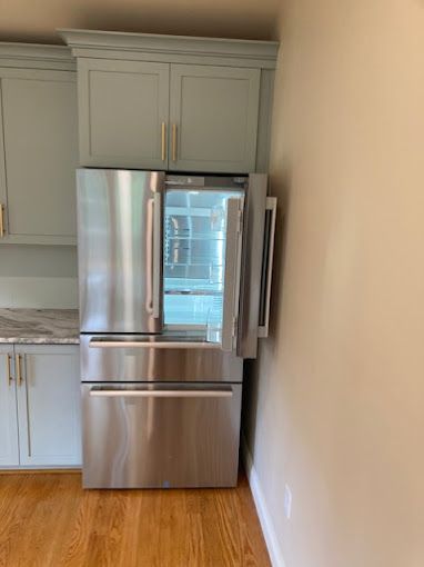 A stainless steel refrigerator is sitting in a kitchen with its door open.