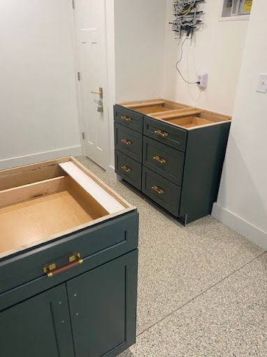A bathroom with green cabinets and drawers being built.