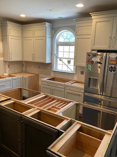 A kitchen is being remodeled with white cabinets and stainless steel appliances.