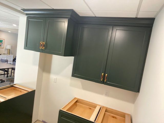 A kitchen with green cabinets and a wooden counter top.