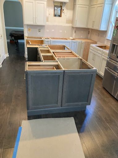 A kitchen with gray cabinets and white cabinets is being remodeled.
