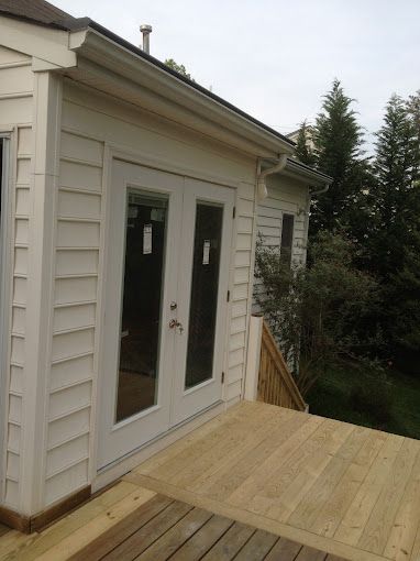 A white house with a wooden deck in front of it.